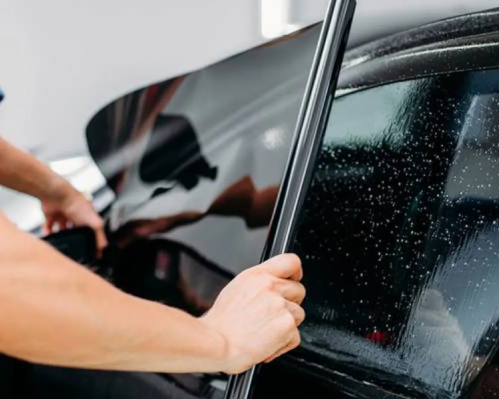 Installer fitting sun film to a car window